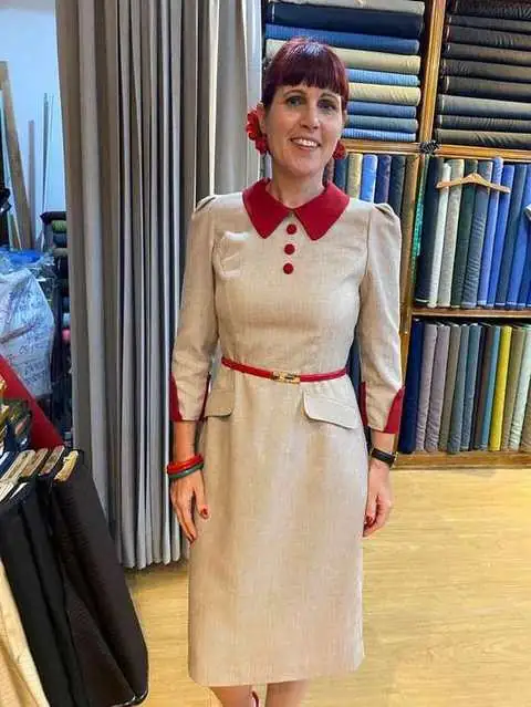 Client in beige vintage-style dress with red collar and belt